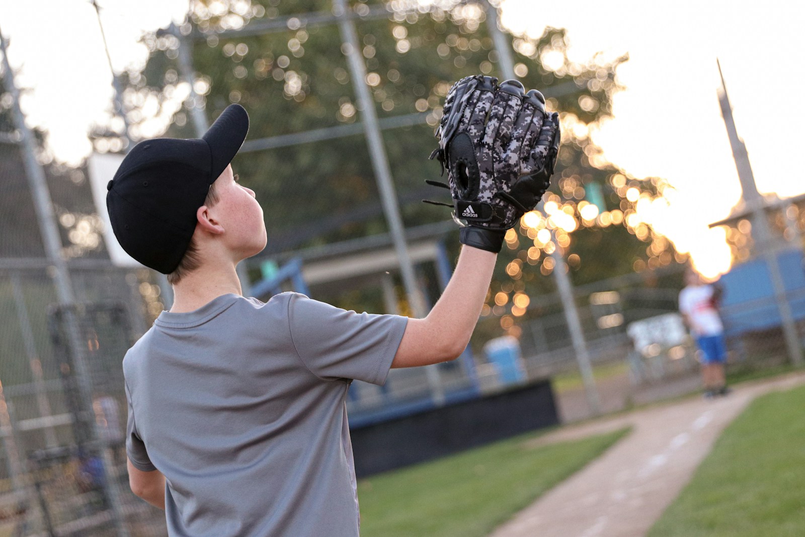 Youth baseball player tracking a fly ball with glove raised above the shoulder